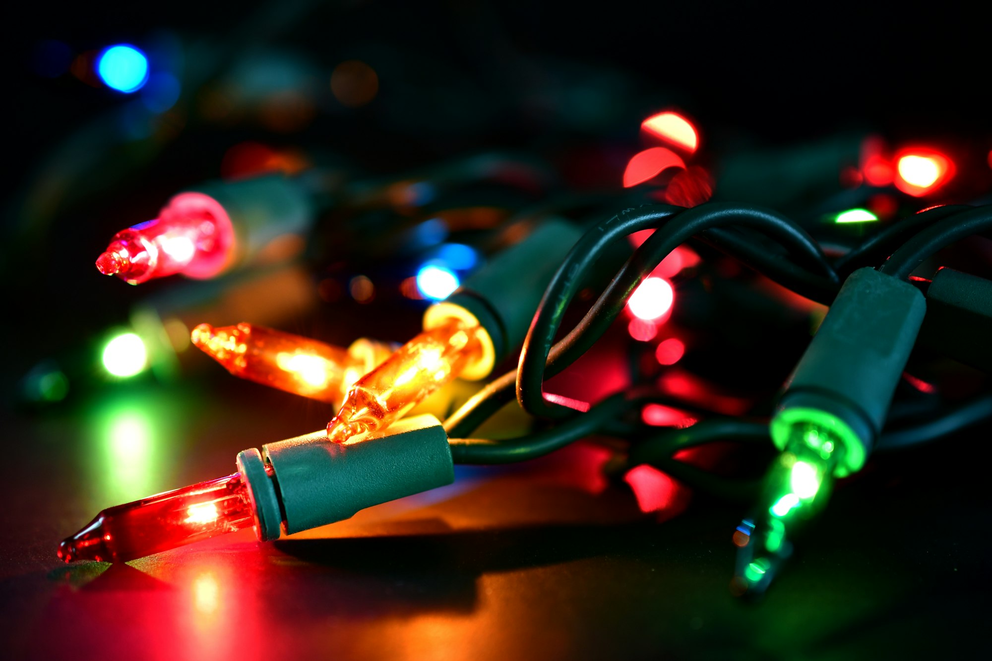 multi-colored-christmas-lights-with-green-wires-tangled-bundle-of-christmas-tree-lights-on-dark